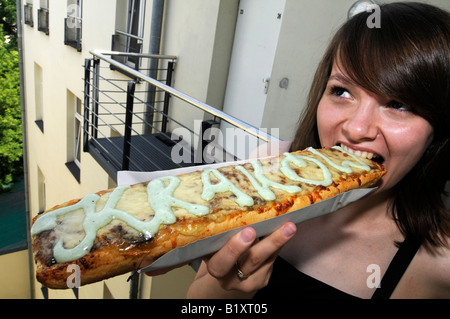 Une jeune fille polonaise de manger un casse-croûte traditionnel appelé 'zapakianka', une sorte de pizza polonais, à Cracovie, Pologne. Banque D'Images