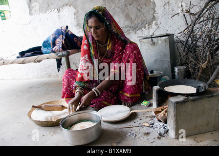 Femme du Rajasthan (Inde) prépare la nourriture. La cuisson à poêle traditionnel de cour dans la maison. Robe typique et des navires. Banque D'Images