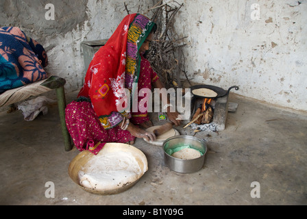 Femme du Rajasthan (Inde) prépare la nourriture. La cuisson à poêle traditionnel de cour dans la maison. Robe typique et des navires. Banque D'Images