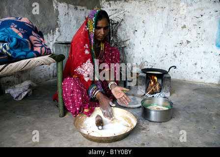 Femme du Rajasthan (Inde) prépare la nourriture. La cuisson à poêle traditionnel de cour dans la maison. Robe typique et des navires. Banque D'Images