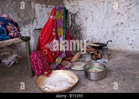 Femme du Rajasthan (Inde) prépare la nourriture. La cuisson à poêle traditionnel de cour dans la maison. Robe typique et des navires. Banque D'Images