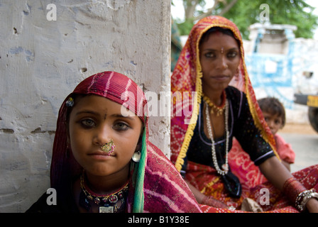 Portrait d'une jeune fille Rajasthani portant une robe typique assis avec sa mère et sa sœur cadette à l'arrière-plan (Inde) Banque D'Images