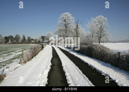 Village de Aldersey, Cheshire, Angleterre. Hiver ensoleillé neige scène d'une route de campagne et de fermes dans la campagne du Cheshire. Banque D'Images