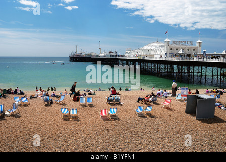 Les touristes profiter du soleil sur la plage de Brighton Pier avec en arrière-plan Banque D'Images