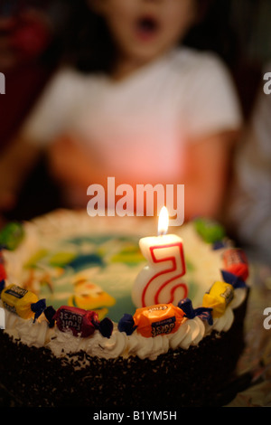 Petite fille de cinq ans souffle les bougie sur son gâteau d'anniversaire à son parti Banque D'Images