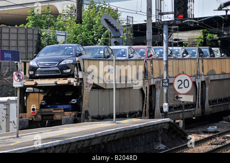 Train de fret chargé avec des nouveaux véhicules de la station en passant par l'usine Banque D'Images