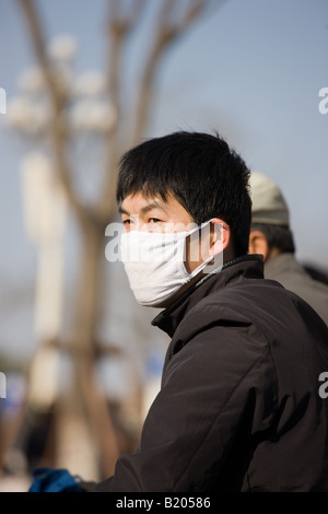 Le cycliste porte un masque dans une circulation intense pollution Beijing Chine Banque D'Images