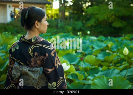 Femme portant un kimono japonais reflétant dans un étang de lotus Banque D'Images