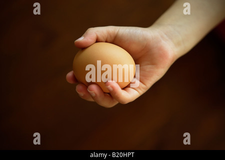 Jeune fille âgée de quatre ans est titulaire d'oeuf de poule dans sa main Banque D'Images