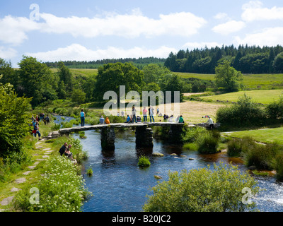 Les touristes appréciant les vieux Clapper Bridge à Postbridge Dartmoor dans le Devon UK Banque D'Images