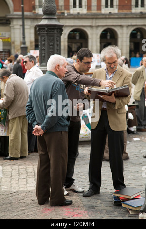 Espagne Madrid collectionneurs commerce et vente de collections dans la Plaza Mayor le dimanche matin les hommes voir carnets de timbres Banque D'Images