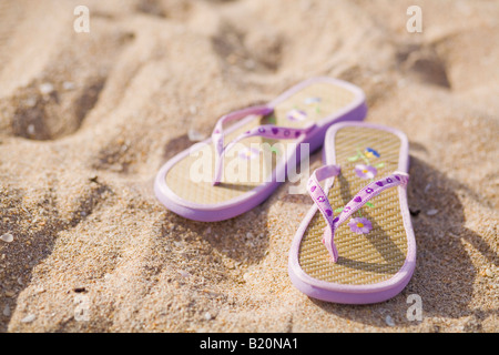 Paire de tongs violet sur la plage. Banque D'Images