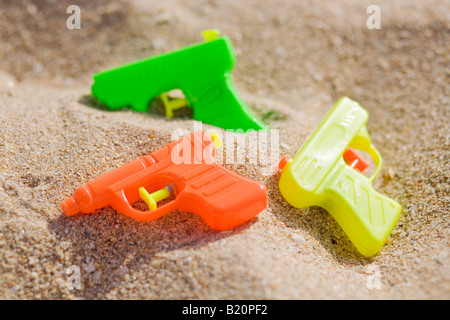 Les pistolets à eau colorés dans le sable sur la plage. Banque D'Images