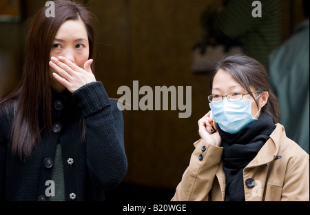 Les jeunes femmes chinoises avec couverts bouche à Hong Kong, Chine Banque D'Images