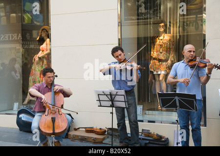 Espagne Madrid trois musiciens jouant des mâles et de violoncelle violons en avant du store windows avec des mannequins Calle Preciados Banque D'Images