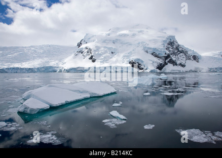 Beau paysage voyage pittoresque blue iceberg flottant dans la banquise, la neige a couvert Neko Harbour Antarctique entouré par des réflexions et des montagnes enneigées Banque D'Images