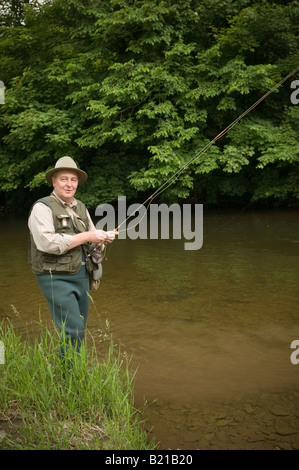 Un homme d'âge moyen la pêche à la mouche de la truite dans la rivière Severn à Llandinam rural Powys Pays de Galles UK, après-midi d'été Banque D'Images