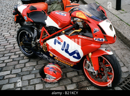 Ducati 999R de l'Angleterre en moto sport racing livery parrainage avec les autocollants sur une rue pavée avec casque rider Banque D'Images