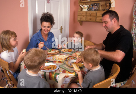 Jeune famille triplet avec fils et une fille d'avoir autour de la table de repas Banque D'Images