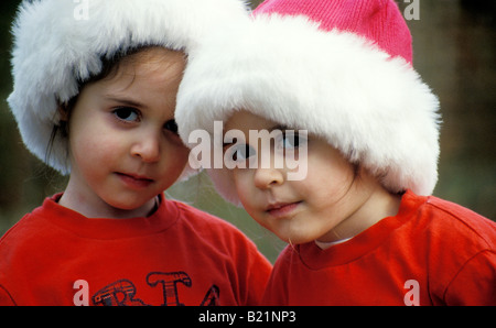 Twin girls wearing red santa outfits Banque D'Images