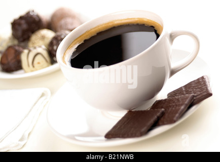 Tasse blanche avec du café noir et trois après le dîner menthes au chocolat avec chocolats plus flou en arrière-plan Banque D'Images