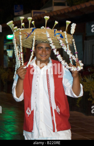 Portrait d'un vertical vendeur fleur traditionnelle avec un grand panier de fleurs de jasmin 'mechmoum' sur sa tête pendant la nuit. Banque D'Images