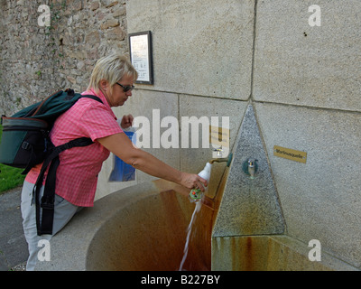 Femme d'âge moyen de prendre l'eau de fontaine bien pour l'eau du spa dans les jardins du spa dans la ville de Bad Orb Hesse Allemagne Banque D'Images