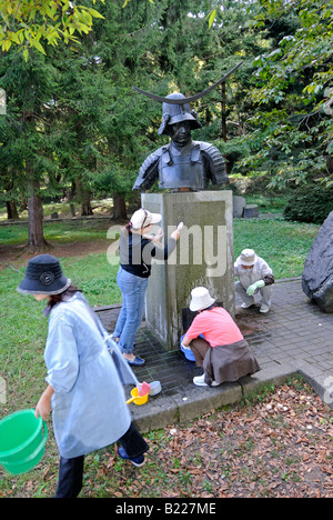 Laver les bénévoles des statues du puissant seigneur féodal date Masamune au Château Aoba Sendai au Japon Banque D'Images