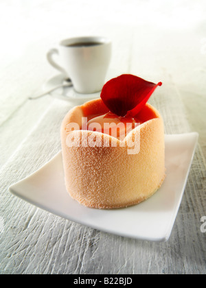 Gâteau au chocolat blanc avec une éponge et garniture aux fraises, recouvert de poudre de chocolat blanc rose et de café dans un cadre de table Banque D'Images