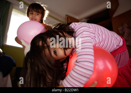 Garçon de 6 ans et sa sœur âgée de 4 ans jouer avec des ballons dans leur chambre à coucher. Course mixte anglais asiatique Banque D'Images