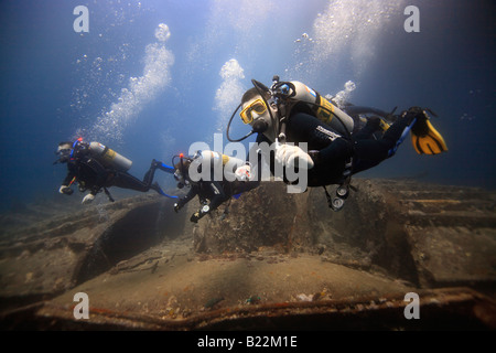 Trois plongeurs d'explorer l'épave du SS Thistlegorm dans l'égyptien de la Mer Rouge. Banque D'Images