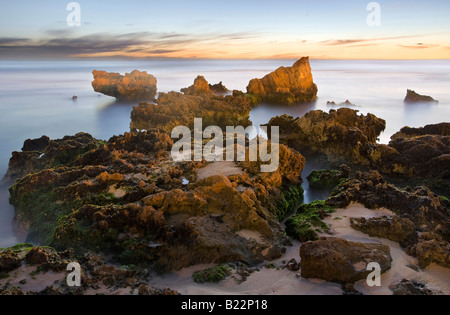 Les roches calcaires sur la côte à Trigg Beach à Perth, Australie occidentale. Une longue exposition prises au coucher du soleil Banque D'Images