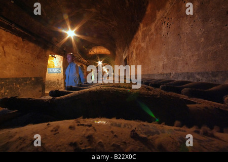 Reims, France. Un homme marche par près d'une ligne de vieilles bouteilles de champagne à la cave de la Maison de Champagne Pommery. Banque D'Images