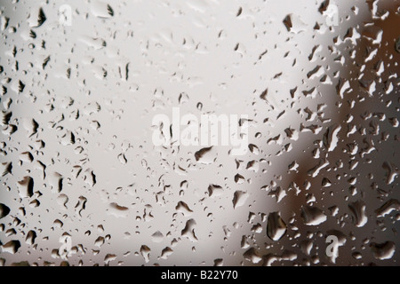 Recueillir des gouttes de pluie sur un carreau de fenêtre sur un ciel couvert humide gris 24. Banque D'Images