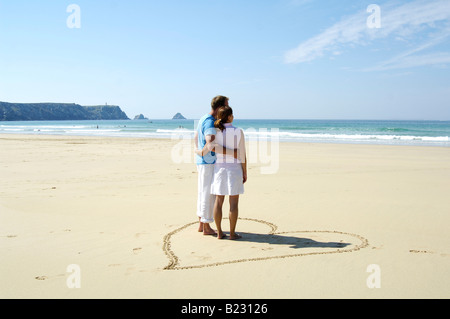 Vue arrière du couple standing in heartshape sur beach Banque D'Images