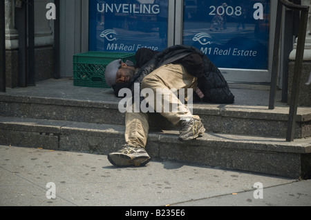 Un sans-abri dort sur les étapes d'un bâtiment dans le centre de Manhattan. Banque D'Images