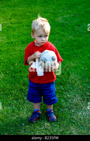 Deux ans très jeune joueur de foot garçon blond Holding Soccer Ball Banque D'Images