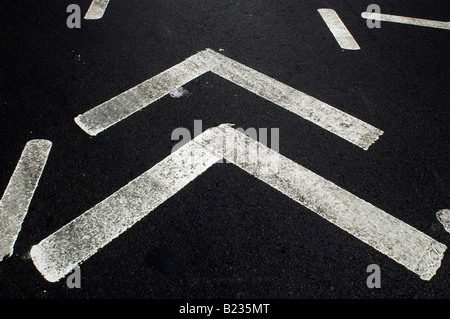 Close up de signalisation des voies de circulation thermique blanc en forme de V sur un asphalte noir street Banque D'Images