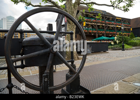 Roue de commande d'un pont à St Katharine's Dock, Londres avec le Dickens Inn dans l'arrière-plan. Banque D'Images