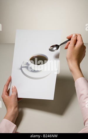 Une femme tenant une photo d'une tasse à café et une cuillère Banque D'Images