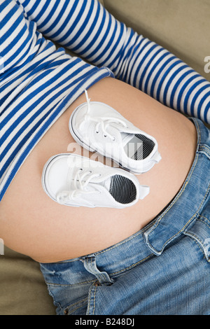 Chaussures bébé sur un estomac enceintes Banque D'Images