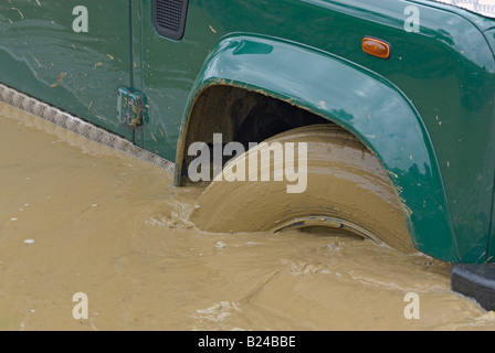 Land Rover la conduite hors route à travers une route inondée à Bining, France. Banque D'Images