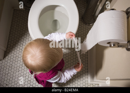 Petite fille de déchirer le papier de toilette Banque D'Images