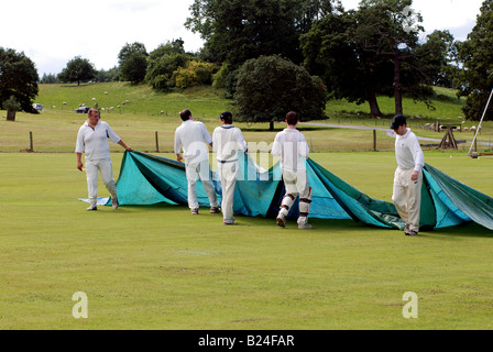 Joueurs de cricket Village de retirer les capots de pitch, Ragley Hall, Warwickshire, England, UK Banque D'Images