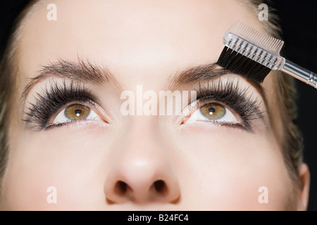 Woman brushing her eyebrows Banque D'Images