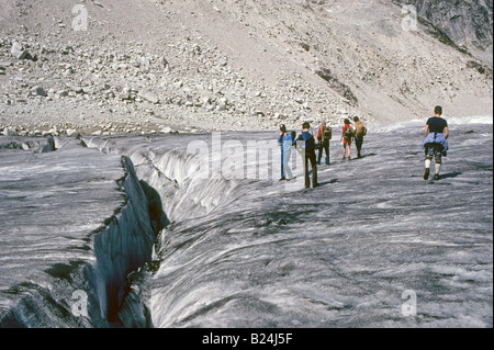 Randonneurs dans le haut pays de la crête des montagnes Bugaboo à pied sur un glacier et d'examiner une grande crevasse dans la glace Banque D'Images