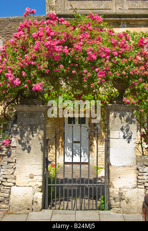 Rose Pink Rambler surmontant une barrière métallique et l'entrée en pierre d'une propriété personnelle en Angleterre Banque D'Images