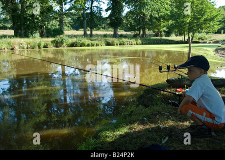 Stock photo d'un garçon de huit ans la pêche au bord d'un lac, la photo a été prise dans la région de France Banque D'Images