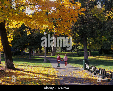 Deux bonnes amies jouer dans les feuilles qui tombent pendant le pic de l'automne dans Drake Park dans le centre-ville de Bend Oregon Banque D'Images