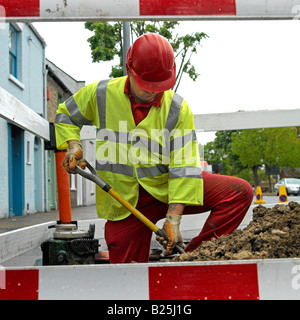 Ingénieur de l'eau dans un trou creuse pour un bris d'une conduite d'eau Angleterre Royaume-Uni Pas de libération nécessaire face totalement obscurci par hard hat Banque D'Images